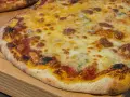 Eine köstliche quattro formaggi Pizza mit geschmolzenem Käse und knusprigem Rand auf einem Holzbrett.