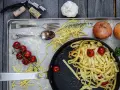 Frische Nudeln aus Hartweizengries, Tomaten, Zwiebeln und Knoblauch auf einem Blech. Ein Festmahl für Genießer!