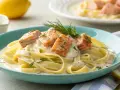 Tagliatelle mit Lachs in cremiger Soße, die durch Zitrone und Sahne mischen verfeinert wird. Garniert mit Dill und Kräutern.