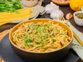 Eine Schüssel mit Thunfisch Pasta, garniert mit Petersilie und Zitronenschale. Oliven und Kapern sind ebenfalls sichtbar.