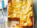 Eine goldbraun überbackene Lasagne mit einer cremigen Käseschicht. Ein Stück ist bereits entnommen, was die saftige Füllung offenbart. Diese Pistazien Lasagne sieht köstlich aus!