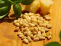 Frische Pinienkerne, Basilikum und Parmesan auf Holzbrett. Achten Sie auf die Pinienkerne Haltbarkeit für Pesto.