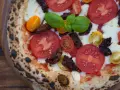 Pizza mit frischen Tomaten, Mozzarella, Basilikum und intensiven pomodorini secchi.
