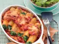 Cannelloni ricotta-spinat italienisch, überbacken mit Tomatensauce und Käse, serviert in einer Auflaufform.