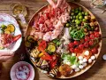 Italienische Snacks Rezepte: Eine üppige Platte mit Aufschnitt, gegrilltem Gemüse, Oliven, Tomaten und Mozzarella. Perfekt für einen Aperitif!