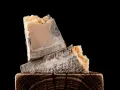 Zwei Stück verdorbener Parmesan mit blau-grünem Schimmel, die auf einem Holzklotz liegen. So sieht schlechter Parmesan aus.