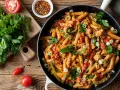 Herzhafte Penne mit Hähnchen, Paprika und Tomaten in einer cremigen Sauce. Ein tolles Beispiel für ausgefallene Pasta Rezepte, garniert mit frischer Petersilie und Frühlingszwiebeln.