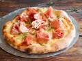 Eine köstliche biancaneve pizza mit zartem Schinken und Rosmarin, auf einem Pizzastein serviert.