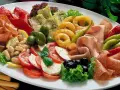Eine üppige antipasti platte mit Schinken, Salami, Oliven, Artischocken, Tomaten-Mozzarella-Salat und frittierten Ringen.
