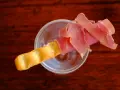 Ein knuspriger Grissini, umwickelt mit zartem Schinken, ruht in einem Glas. Perfekt für den kleinen Hunger.