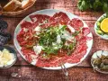 Carpaccio: hauchdünne Rindfleischscheiben mit Rucola, Parmesan und Kapern. Ein Klassiker der italienischen Küche.