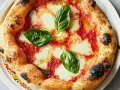 Eine original Pizza Margherita mit geschmolzenem Mozzarella, Tomatensauce und frischem Basilikum. Der Rand ist goldbraun und leicht angekohlt.