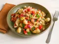 Panzanella rezept: Ein rustikaler Salat mit Brotstücken, Tomaten, Gurken und roten Zwiebeln in einer grünen Schüssel.