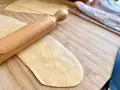 Mit einem Nudelholz wird Teig für **ravioli selber machen ohne maschine** auf einem Holzbrett ausgerollt.