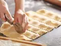 Hände schneiden mit einem Teigrädchen frische Ravioli. Das sind die besten Ravioli Rezepte zum Nachmachen.
