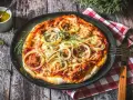 Italienisches Thunfisch Pizza Rezept: Eine köstliche Pizza mit Thunfisch, Zwiebeln und Käse, serviert auf einem Holztisch.