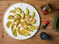 Gebratene Zucchinischeiben auf einem Teller, beträufelt mit Öl und Balsamico. Ein köstlicher Zucchini-Salat, bereit zum Genießen.