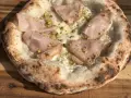 Pizza mit Mortadella und Pistazien auf luftigem pizzateig mit hefe. Der Rand ist knusprig und leicht verbrannt.