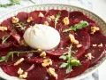 Rote Bete Carpaccio mit Burrata, Walnüssen und Rucola. Ein köstlicher Salat, der auf einem Teller serviert wird.