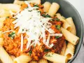 Ein Teller Rigatoni mit Bolognese und Parmesan. Sind Nudeln leicht verdaulich? Diese hier sehen köstlich aus!