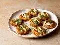A plate of Sarde in Saor, small, round fish cakes drizzled with creamy sauce and fresh dill.