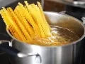 Lange, gewellte vermicelli noodles kochen in sprudelndem Wasser in einem Edelstahltopf.