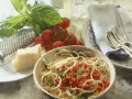 Spaghetti mit frischen Kräutern und gehackten Tomaten aus der Dose. Dazu ein Stück Parmesan, frische Tomaten und ein Grater. Perfekt für einfache Rezepte mit gehackten Tomaten aus der Dose.
