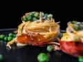 Köstliche italienische Pasta Vorspeisen mit Erbsen und Schinken, auf einem dunklen Teller angerichtet.