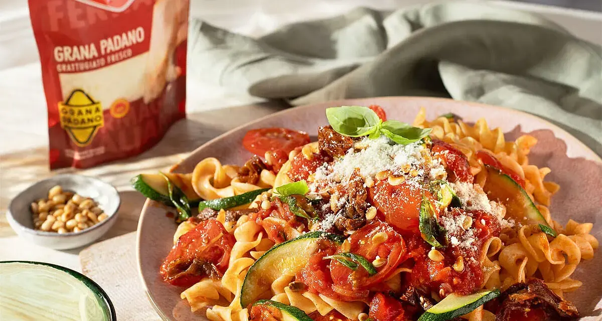 Fusilli mit Tomaten, Zucchini und Pinienkernen, bestreut mit frisch geriebenem Grana Padano. Perfekte parmesan verwendung für ein leichtes Gericht.