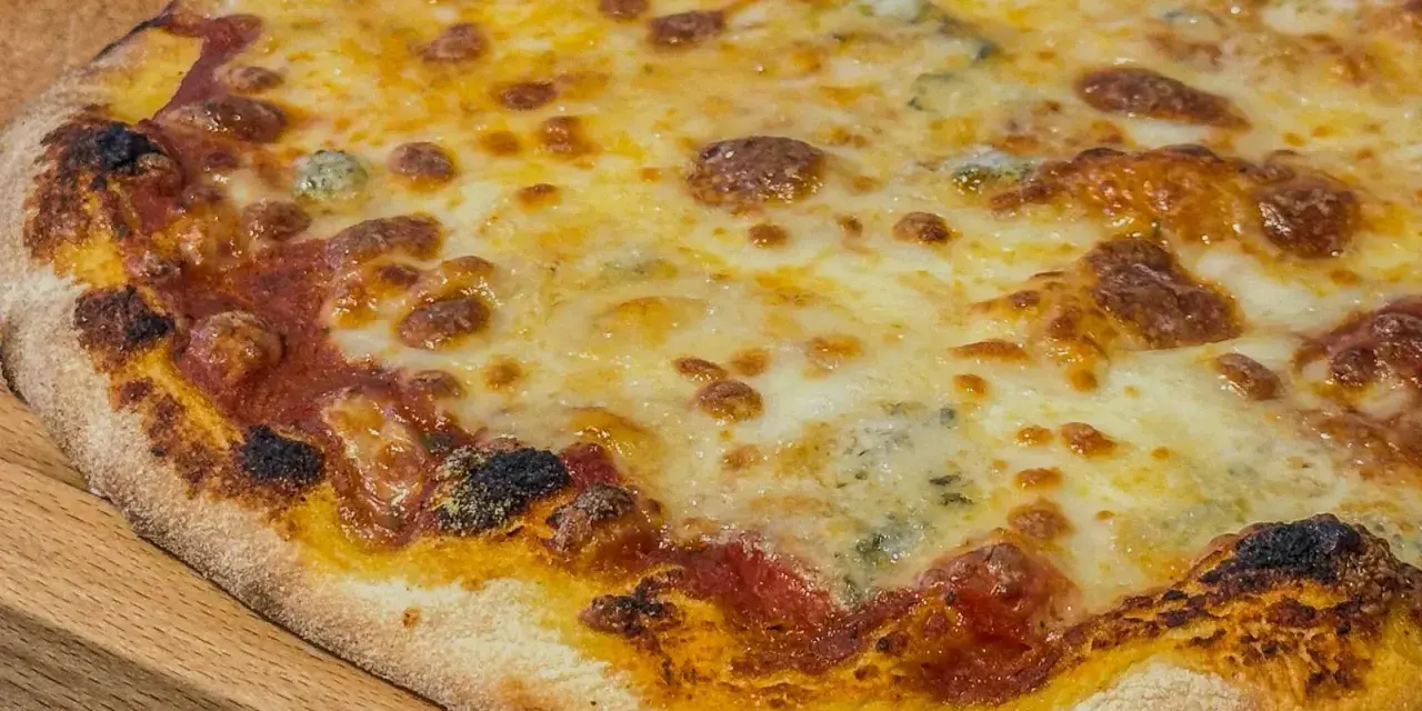 Eine köstliche quattro formaggi Pizza mit geschmolzenem Käse und knusprigem Rand auf einem Holzbrett.