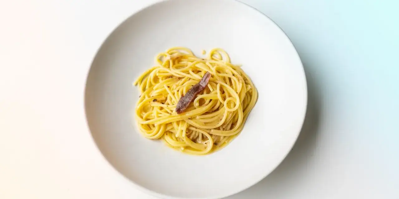 Spaghetti mit einer Sardelle, die zeigt, was sind Sardellen: kleine, salzige Fische, die Pasta verfeinern.
