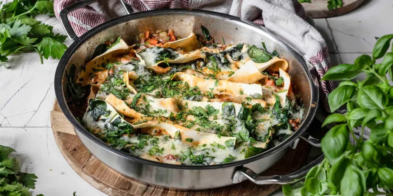 Lasagneplatten vorkochen ohne verkleben: Ein köstliches Gericht mit Spinat und Käse in einer Pfanne, garniert mit frischen Kräutern.
