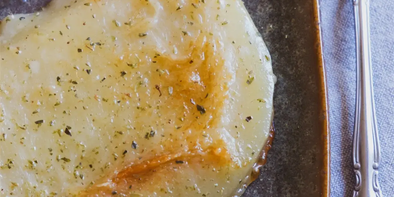 Gebratener Käse mit Kräutern, eine köstliche caciocavallo alternative, auf dunkler Platte mit Gabel.