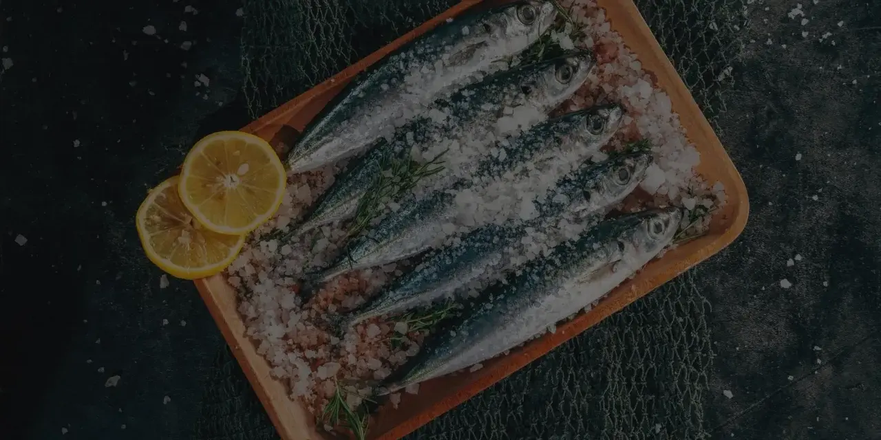 Frische Sardinen und Sardellen, auf einem Holzbrett mit Salz und Zitrone, ein kulinarischer Unterschied.