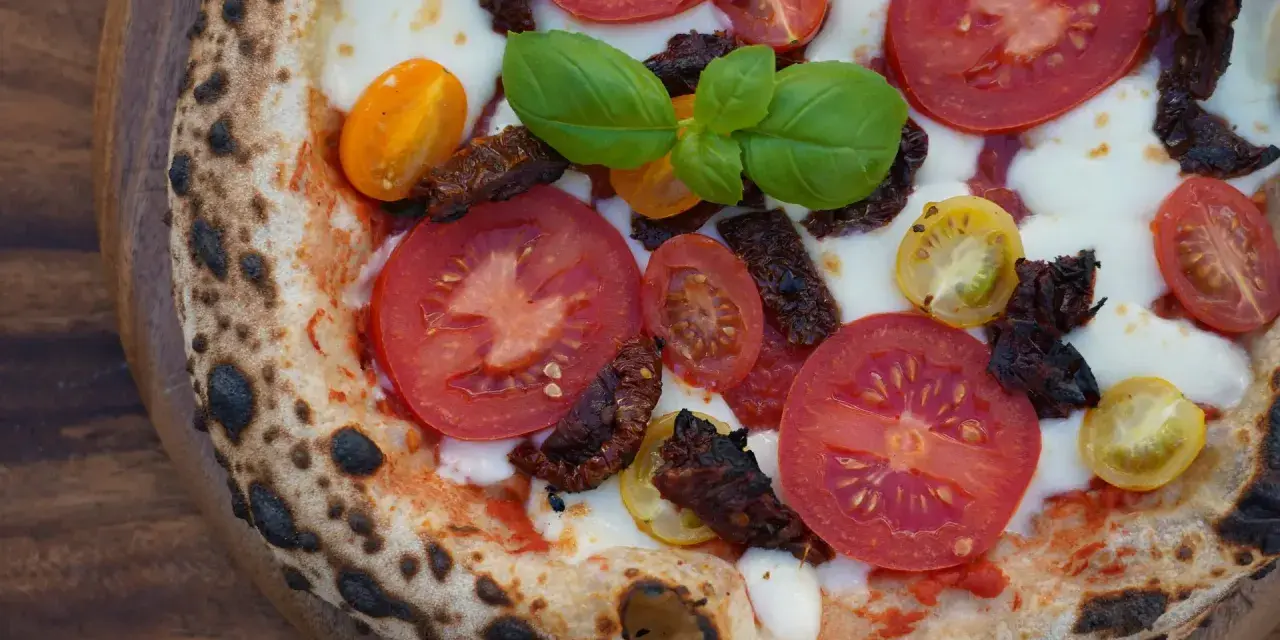 Pizza mit frischen Tomaten, Mozzarella, Basilikum und intensiven pomodorini secchi.
