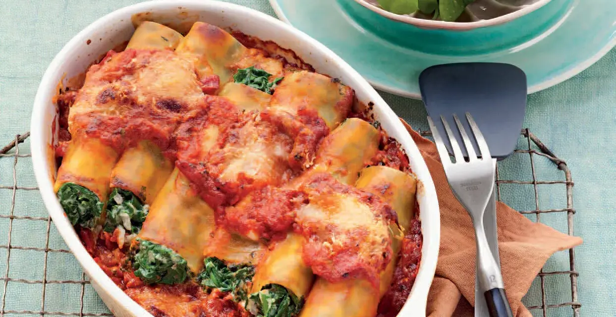 Cannelloni ricotta-spinat italienisch, überbacken mit Tomatensauce und Käse, serviert in einer Auflaufform.