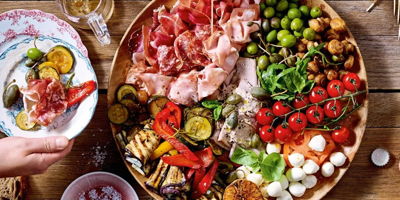 Italienische Snacks Rezepte: Eine üppige Platte mit Aufschnitt, gegrilltem Gemüse, Oliven, Tomaten und Mozzarella. Perfekt für einen Aperitif!