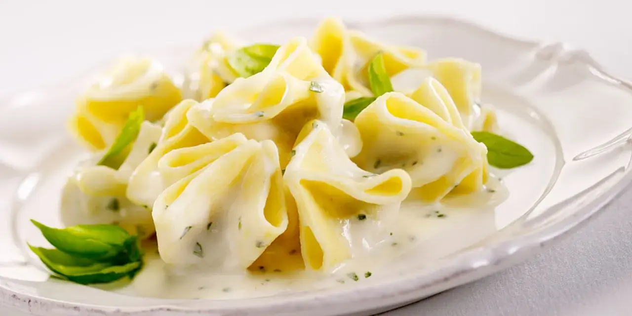 Gefüllte Pasta in cremiger Basilikum-Sahne-Sauce, garniert mit frischen Basilikumblättern. Ein Genuss für Gaumen und Auge.