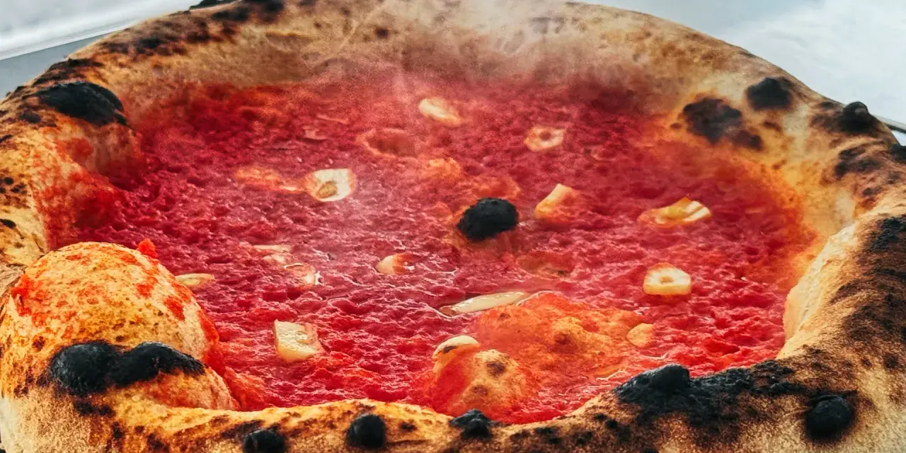 Heiß dampfende Pizza mit knusprigem Rand und leckerer marinara sauce, belegt mit Knoblauch und Oliven.