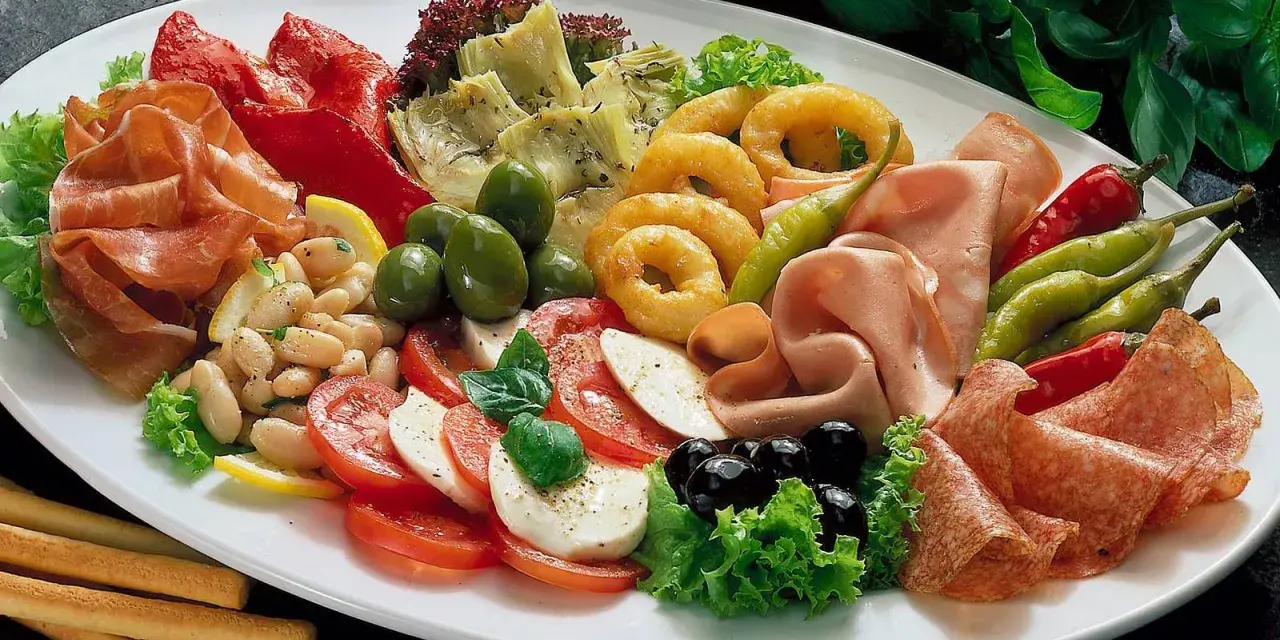 Eine üppige antipasti platte mit Schinken, Salami, Oliven, Artischocken, Tomaten-Mozzarella-Salat und frittierten Ringen.