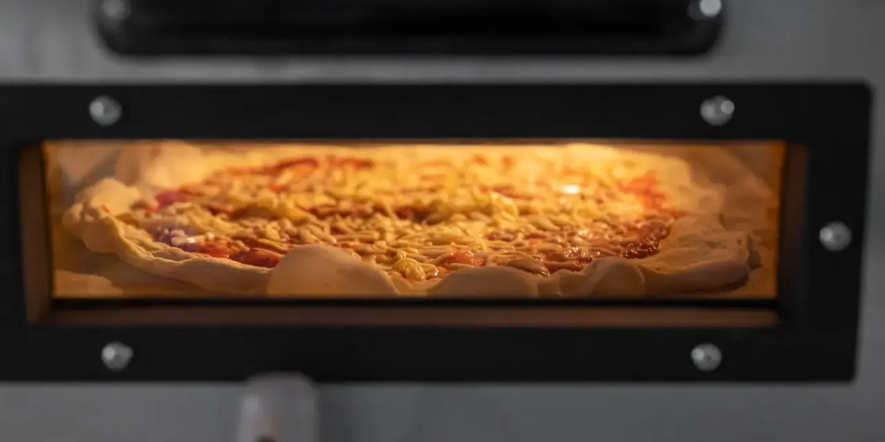 Eine Pizza mit Käse und Tomatensauce backt in einem Ofen.