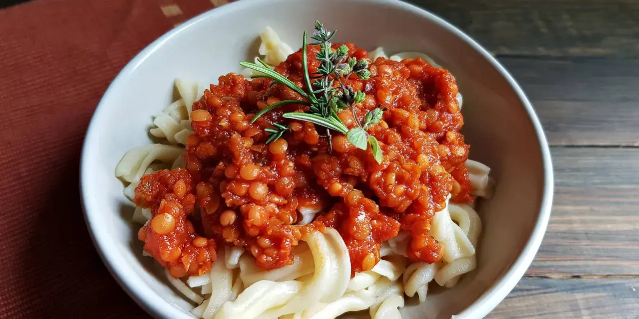 Herzhafte Linsen Bolognese auf Bandnudeln, garniert mit frischen Kräutern. Ein köstliches vegetarisches Gericht.
