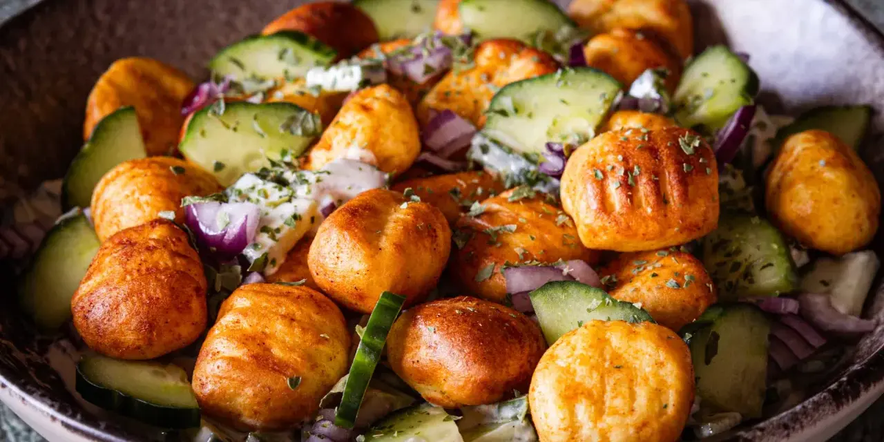 Herzhafter Gnocchi Salat mit Gurken, roten Zwiebeln und einem cremigen Dressing, garniert mit Kräutern.