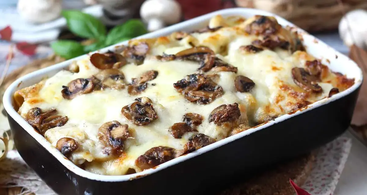 Herzhafte Lasagne al funghi mit geschmolzenem Käse und Pilzen, serviert in einer Auflaufform.