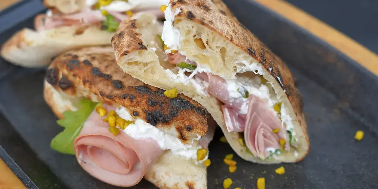 Pizza Mortadella e Pistacchio: knuspriges Brot gefüllt mit Mortadella, cremigem Käse und gehackten Pistazien. Ein Genuss!