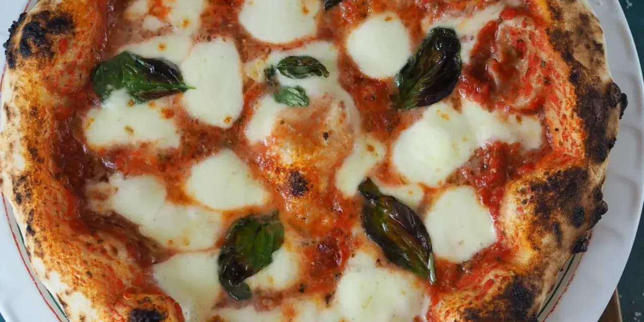 Perfekte Pizza Margherita, wie nach dem Caputo Pizzateig Rezept gemacht, mit geschmolzenem Mozzarella, Tomatensauce und frischem Basilikum.