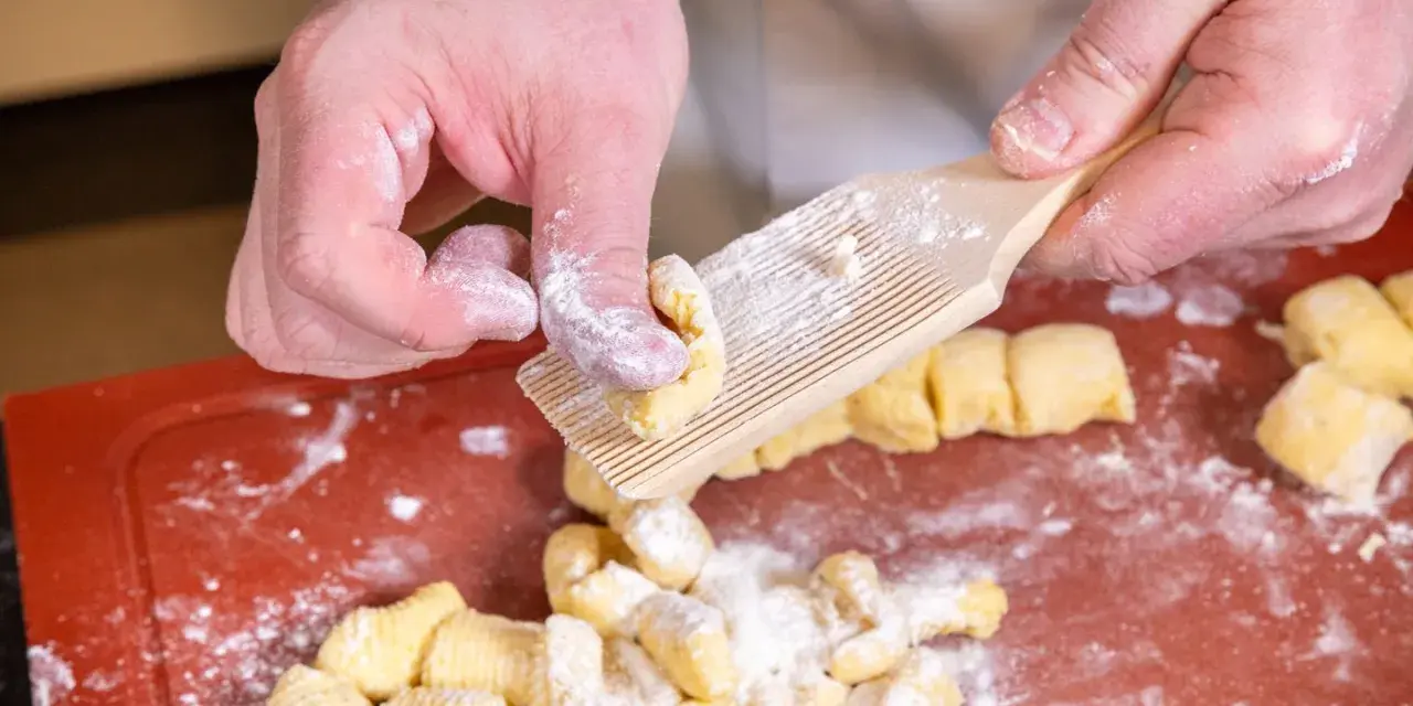 Hände formen Gnocchi mit einem Gnocchi-Brett. Köstliche italienische Gnocchi Rezepte beginnen so.