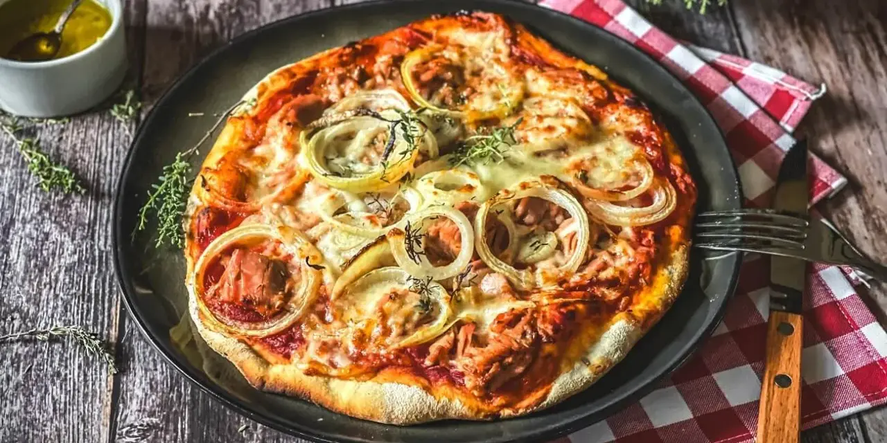 Italienisches Thunfisch Pizza Rezept: Eine köstliche Pizza mit Thunfisch, Zwiebeln und Käse, serviert auf einem Holztisch.
