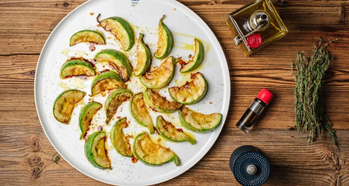 Gebratene Zucchinischeiben auf einem Teller, beträufelt mit Öl und Balsamico. Ein köstlicher Zucchini-Salat, bereit zum Genießen.
