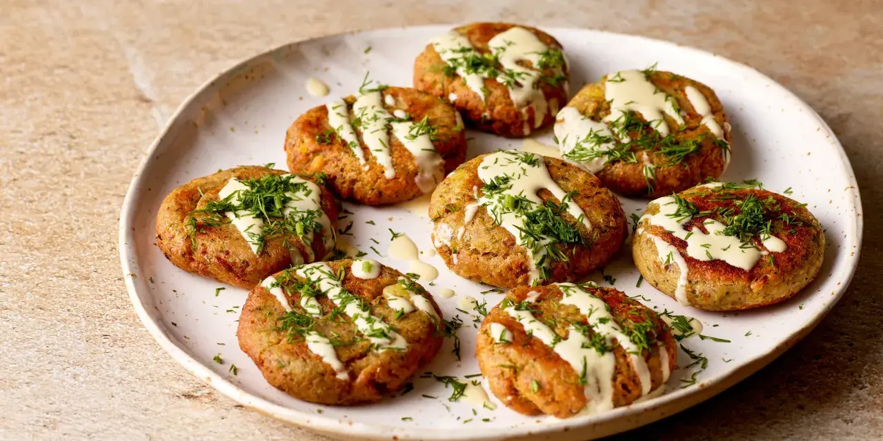 A plate of Sarde in Saor, small, round fish cakes drizzled with creamy sauce and fresh dill.